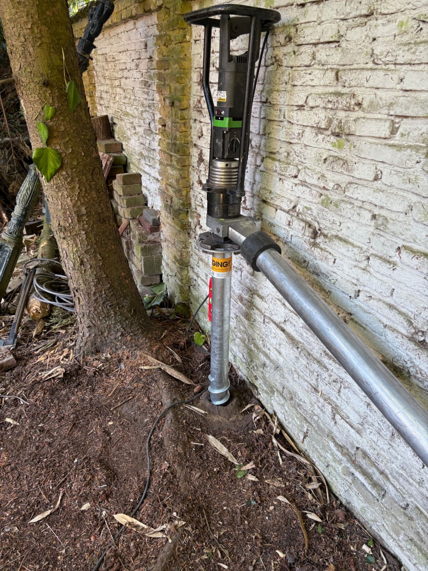 Elektrische handmachine plaatst schroefpaal in besloten tuin